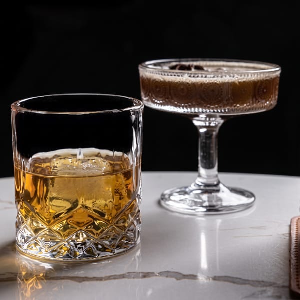 Two cocktails: an amber drink with ice in a rocks glass and a dark frothy drink in a coupe.